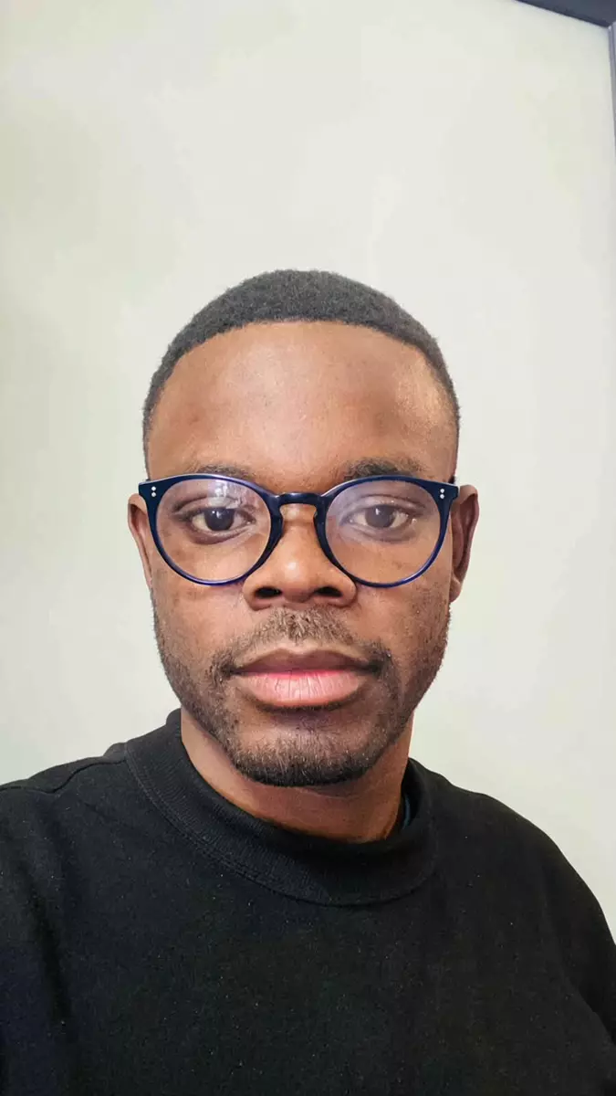 A professional in glasses wearing a black sweater against a plain white background